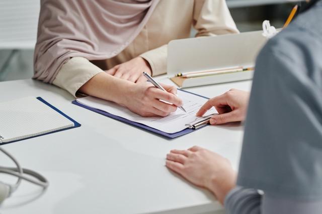 Close up of someone pointing at a clipboard that someone else is filling out.