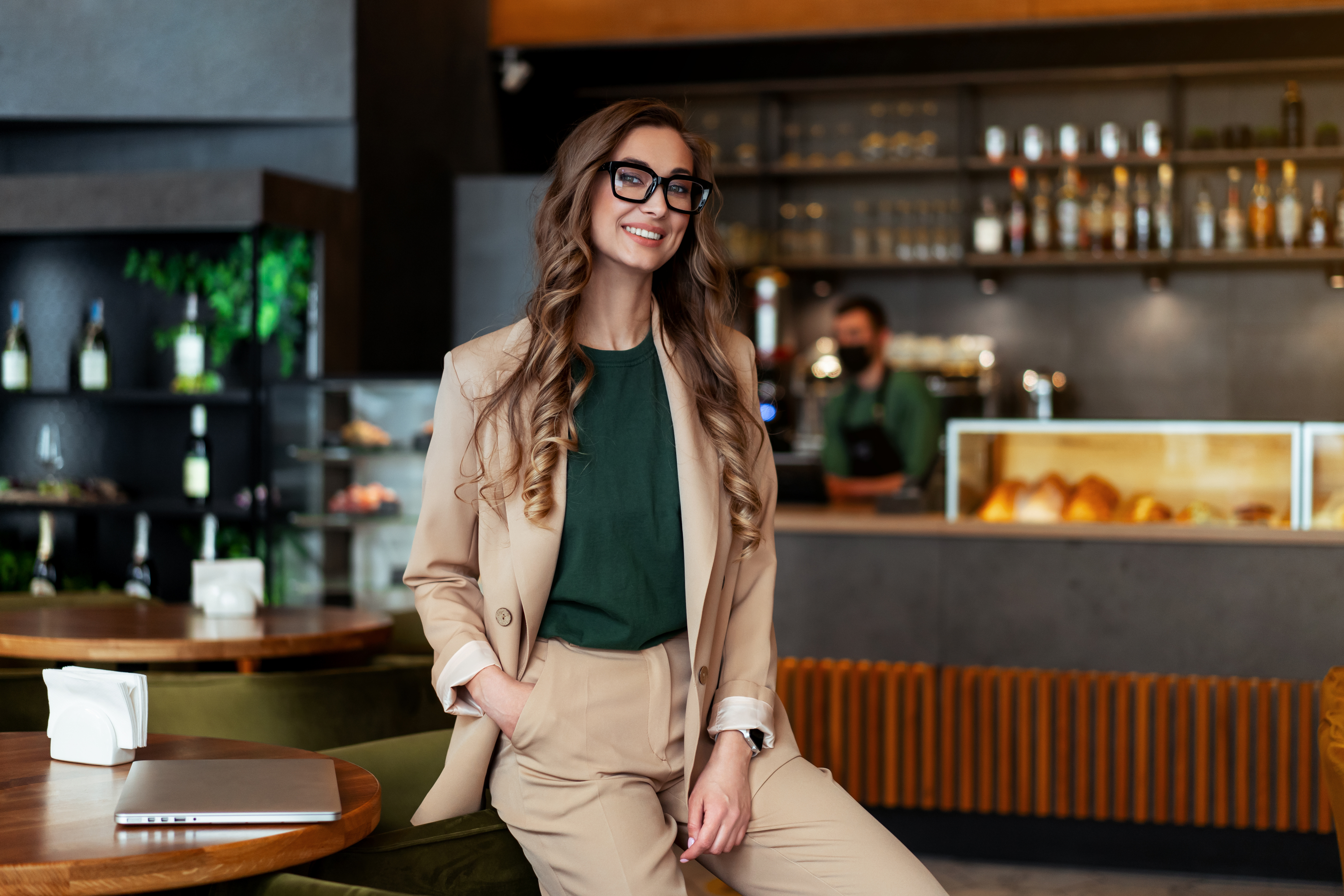 A portrait of a business owner leaning on a table in a restaurant.