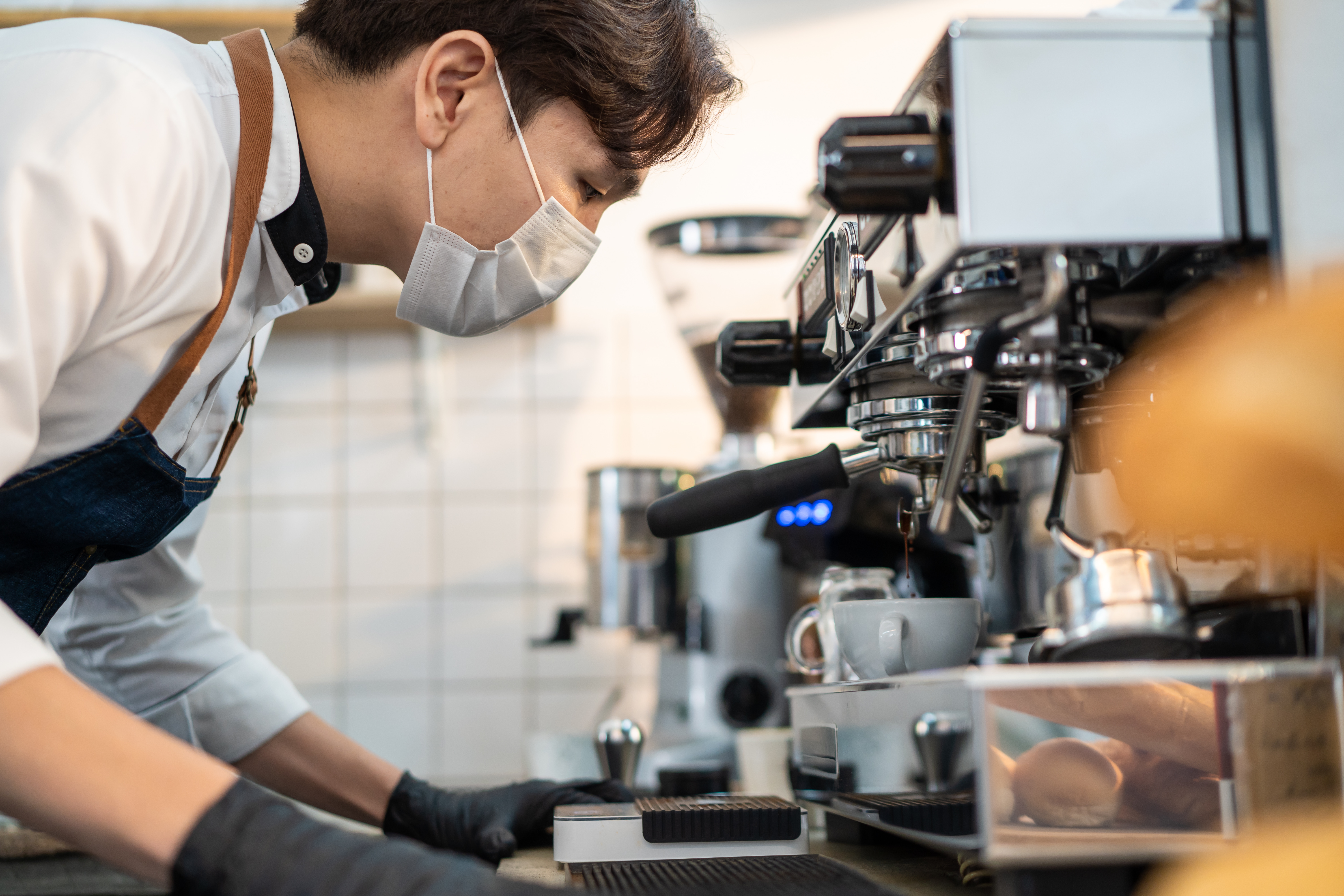 A barista examining an espresso machine.