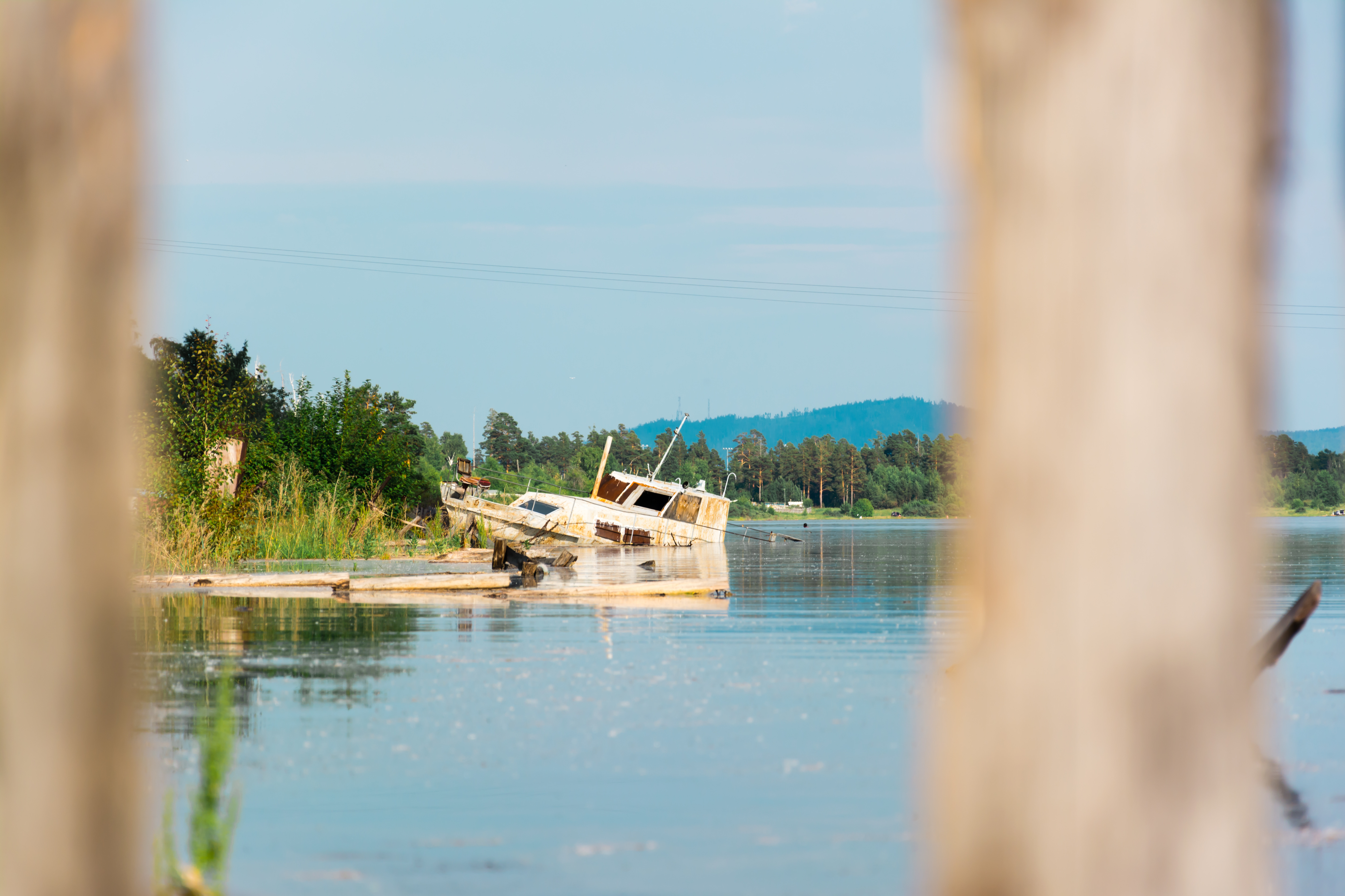 A wide-angle view of a distant wrecked boat beached on a shore.